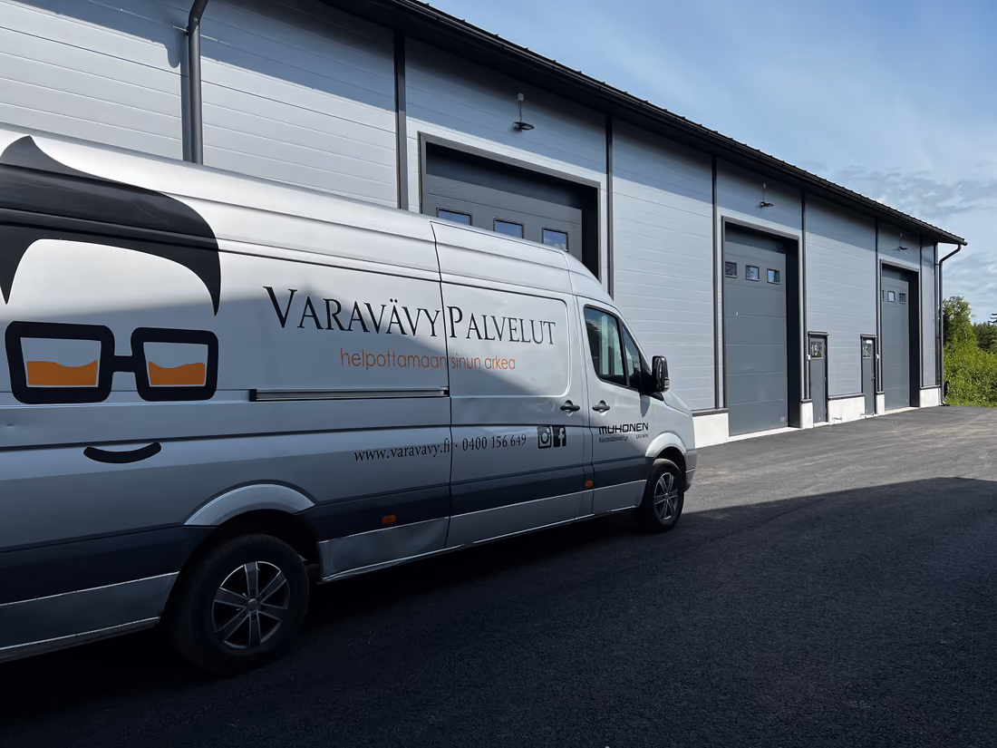 Två av Varavävys flyttbilar lastar framför en kontorsbyggnad